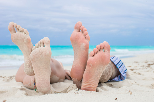 8 Benefits of Walking and Running Barefoot on Sand Man and Woman laying on sandy beach