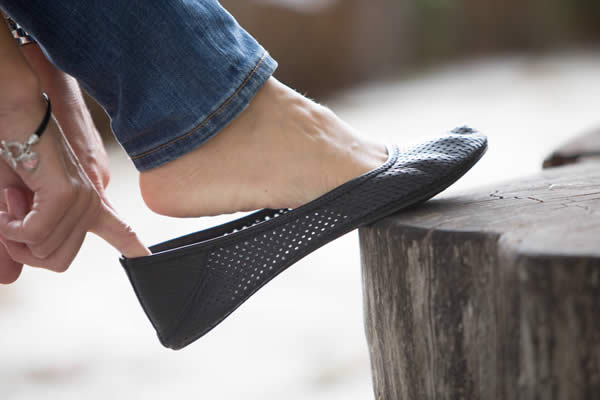 A woman slipping on a barefoot ballet flat to help prevent calluses on feet